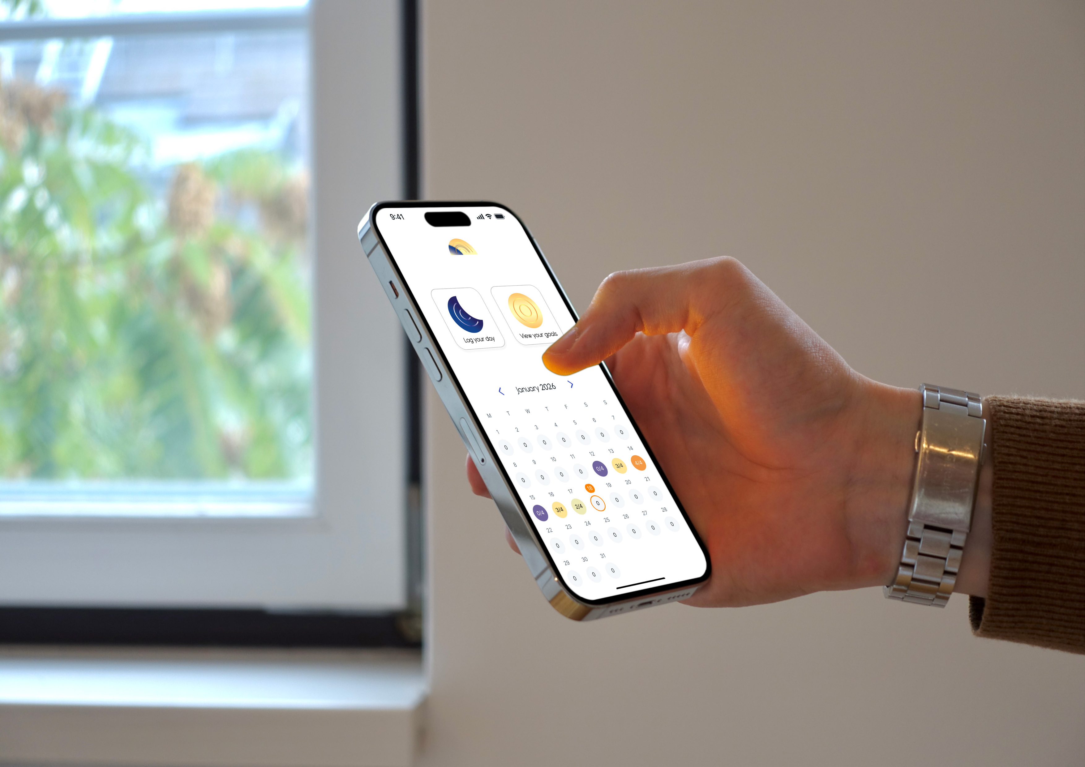 Hand holding a phone showing Cycle’s home screen and reflection calendar beside a window